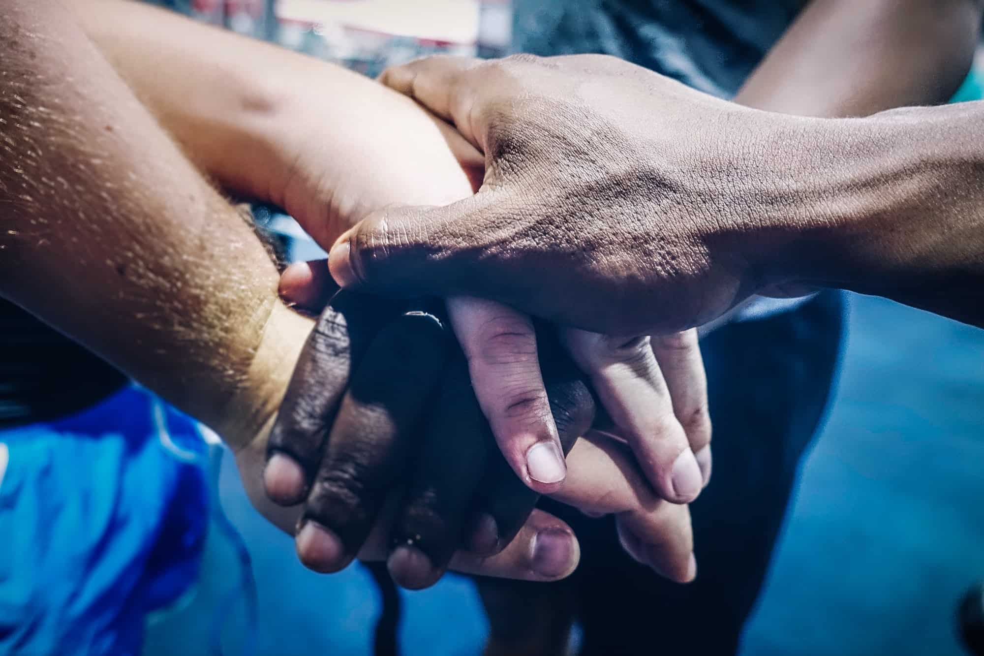 diverse group of people joining hands in unity support and team work gesture close up shot of hands